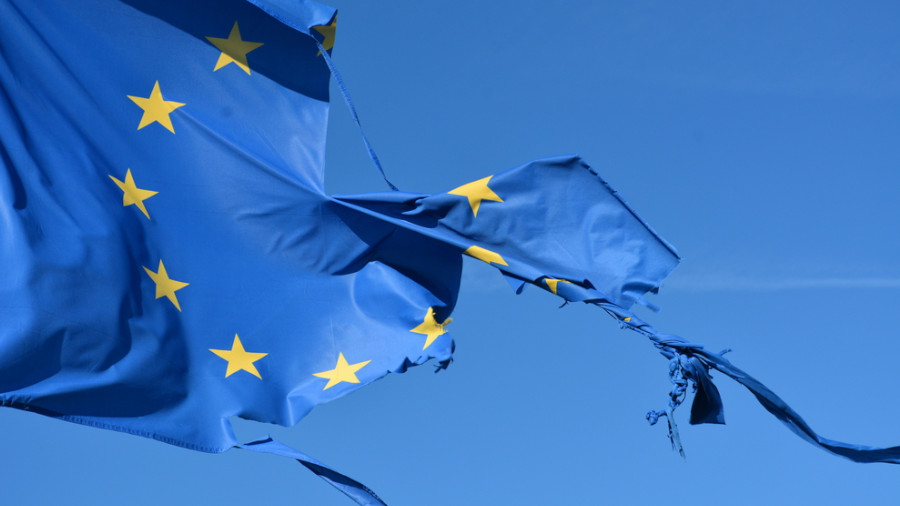 The european union twelve star flag torn and with knots in the wind on blue sky