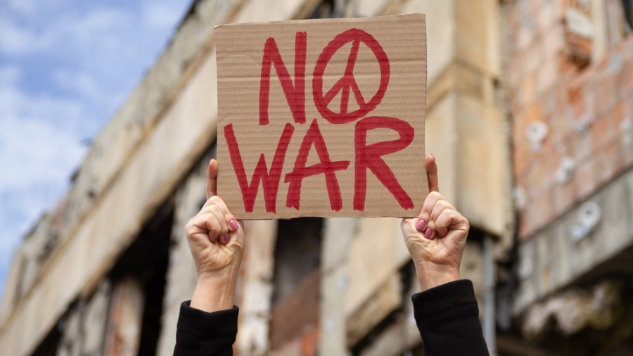 Frauen, die "Kein Krieg"halten, platzieren sich mit Friedenszeichen gegen die Demonstration gegen den Krieg. Abandonierte zerstörte Häuser im Hintergrund. Weibliche Hände mit einem Banner, Anti-Kriegs-Demonstration.