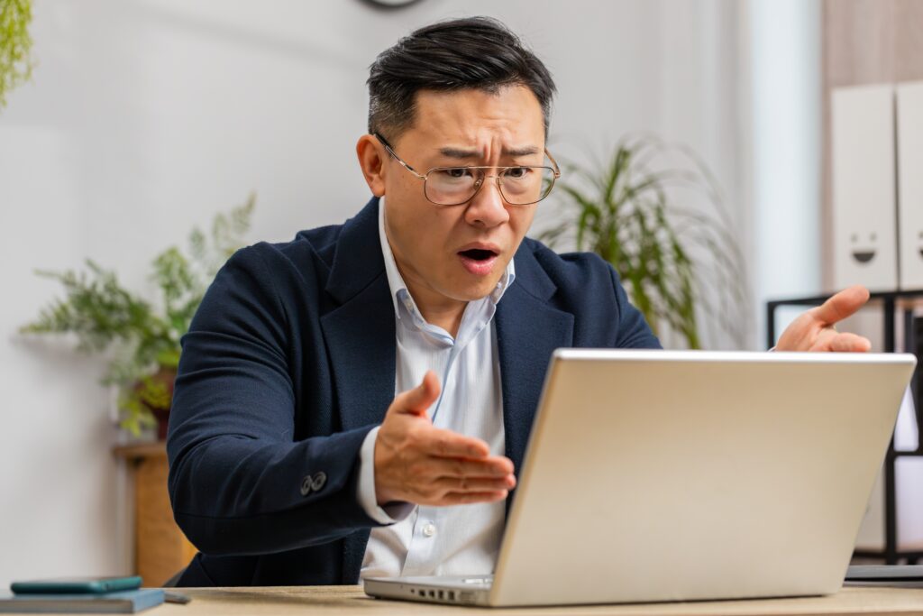 Wütender chinesischer Mann vor dem Notebook