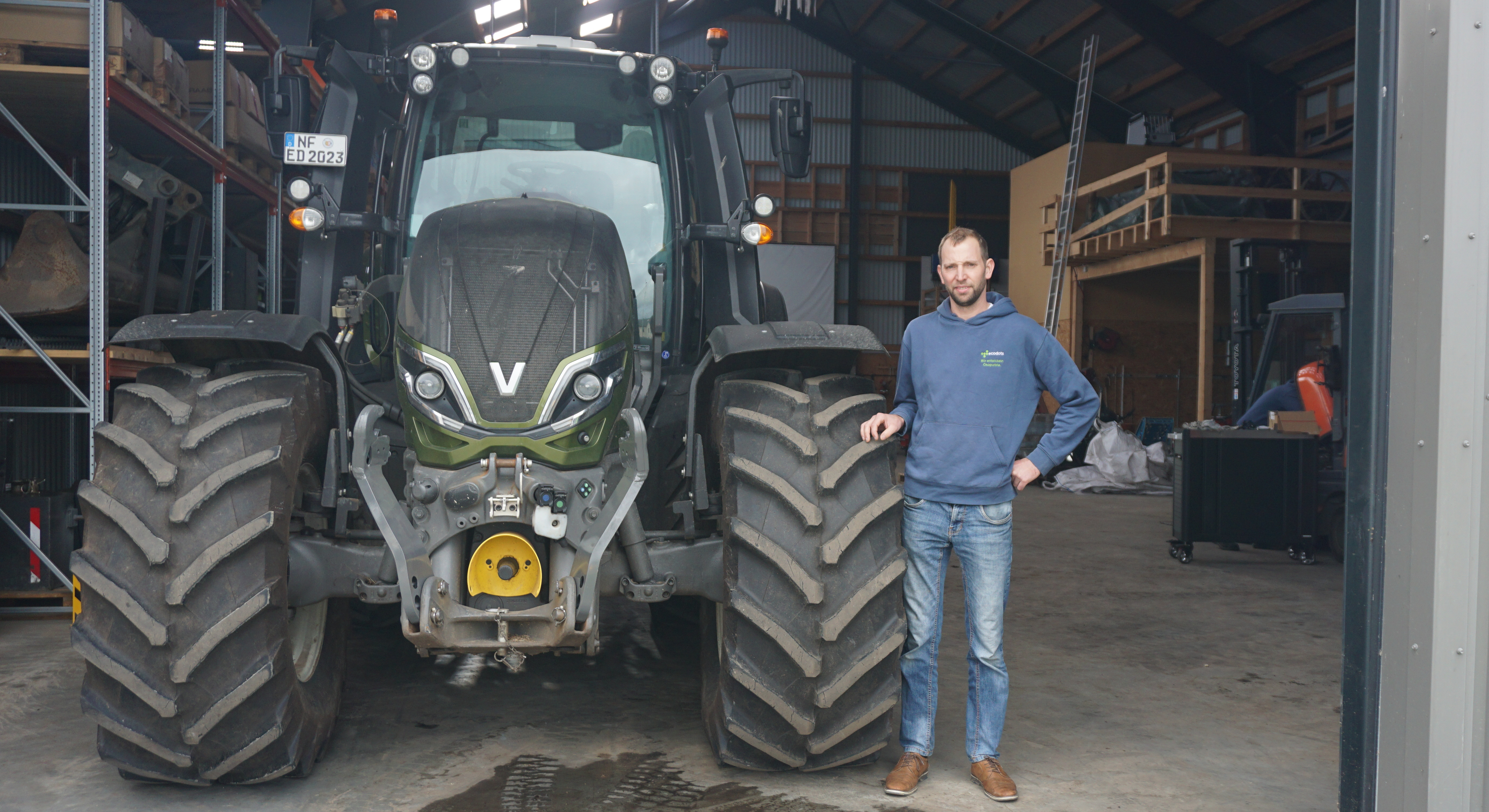 Projektleiter Torge Boysen in der Maschinenhalle von Ecodots. Um einen Mann mit diesen Traktor draußen im Gelände an die Arbeit zu bruingen, brauchtz er zwei Menschen im Büro, die sich um die Bürokratie kümmern.
