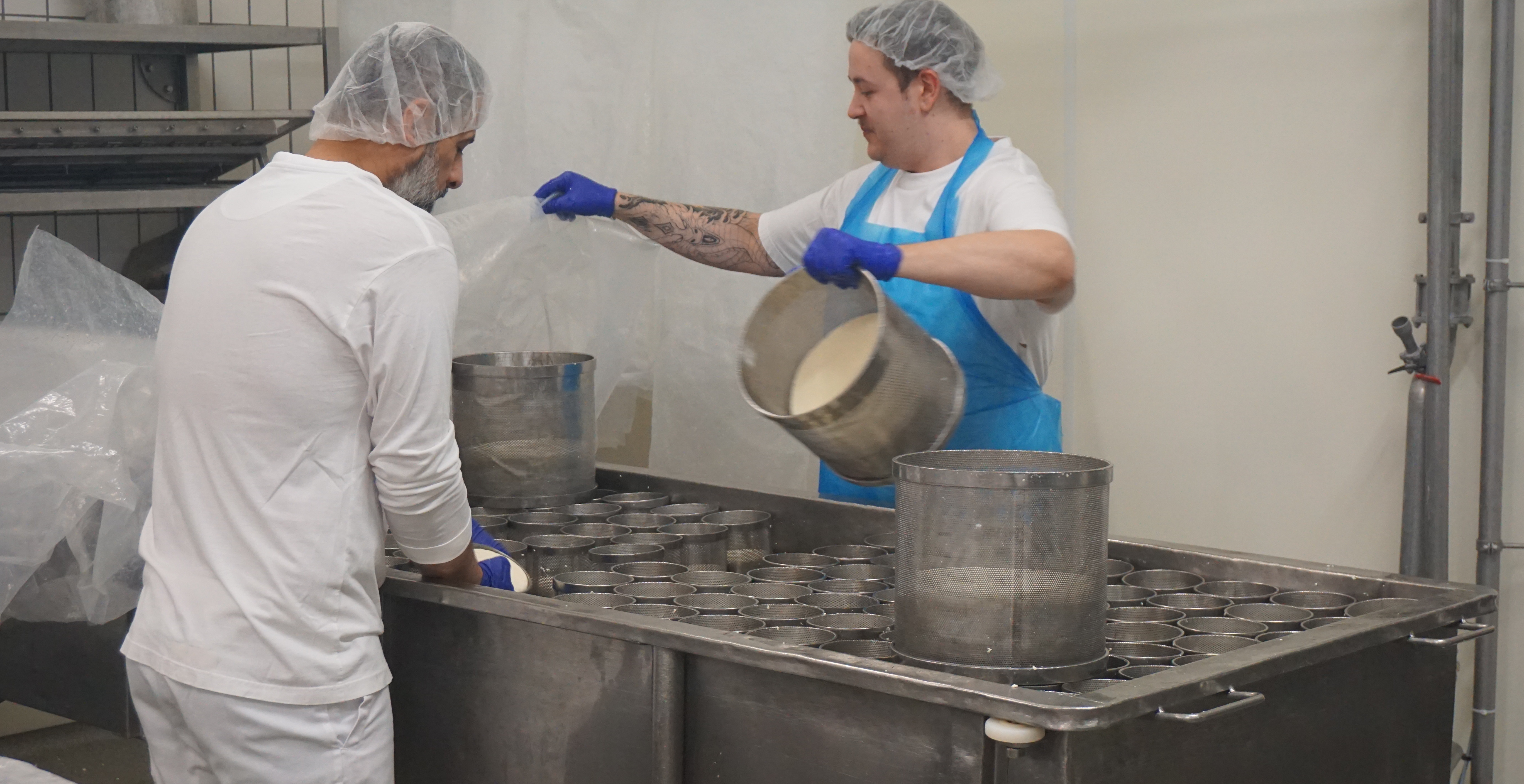 Handarbeit, die bald eine Maschine machen soll - Käser beim Drehen der Formen am Käsetisch.