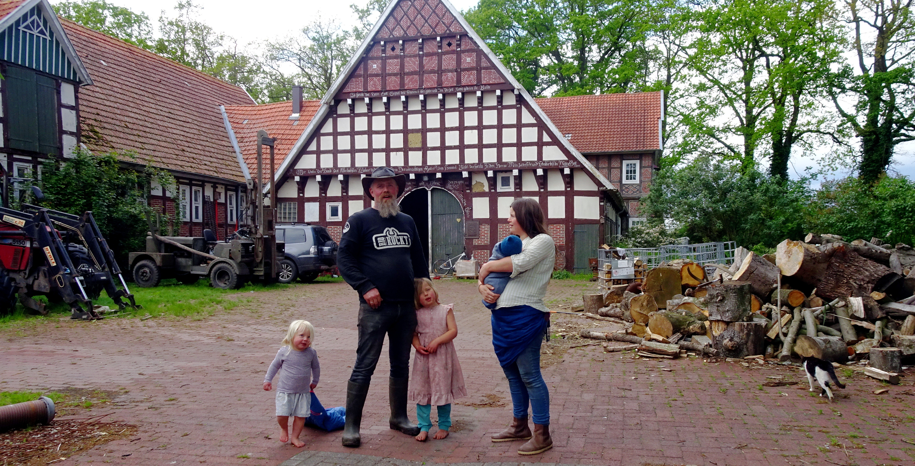 Björn und Johanna Scherhorn mit drei ihrer Kinder vor der Diele, von deren Dachboden Björn damals eine Schwalbe wieder heruntergeleitete, und in deren Fußboden jetzt die Hofkäserei eingebaut werden soll.